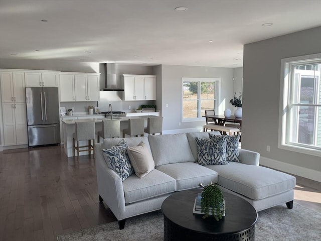 living room with plenty of natural light, sink, and dark hardwood / wood-style floors