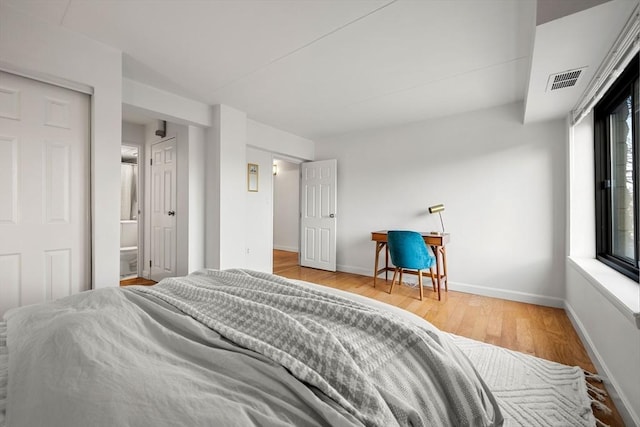 bedroom with ensuite bathroom and hardwood / wood-style flooring