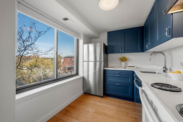 kitchen featuring light hardwood / wood-style floors, blue cabinets, sink, and stainless steel refrigerator