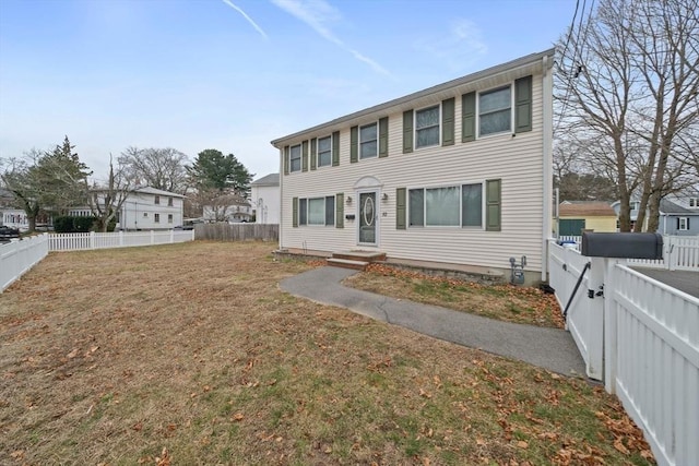 colonial-style house featuring a front yard and a fenced backyard