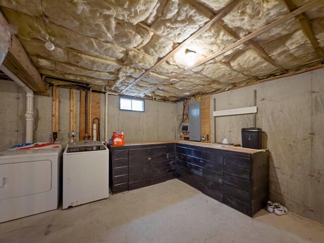 basement with electric panel and washing machine and clothes dryer