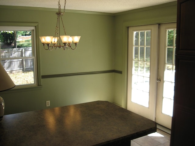 dining space with crown molding, french doors, a textured ceiling, and a notable chandelier