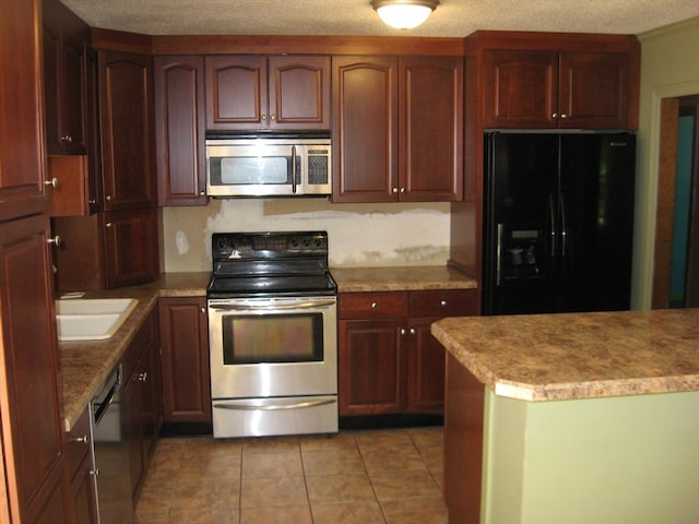 kitchen featuring tile patterned floors, sink, appliances with stainless steel finishes, and a textured ceiling