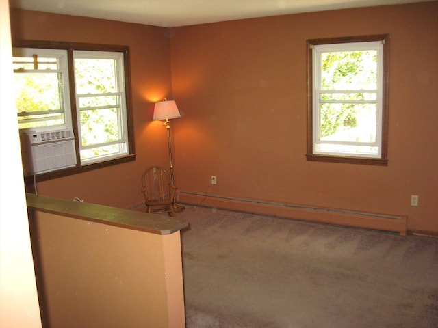 spare room featuring cooling unit, carpet floors, a wealth of natural light, and a baseboard heating unit