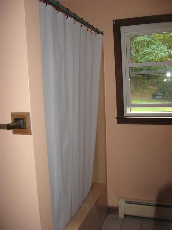 bathroom featuring shower / tub combo, a baseboard radiator, and tile patterned floors