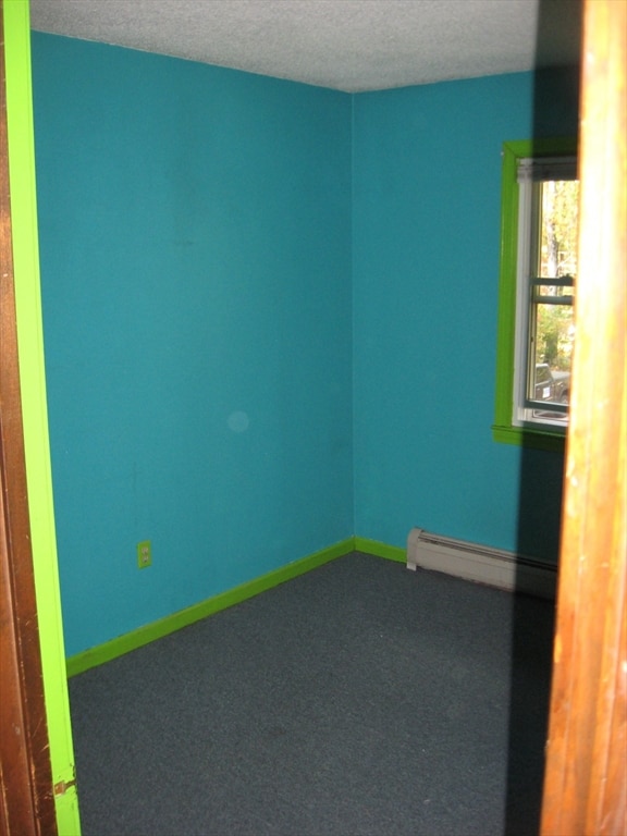 unfurnished room featuring carpet floors, a textured ceiling, and a baseboard radiator