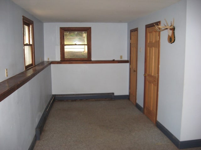 hall with baseboard heating and dark carpet