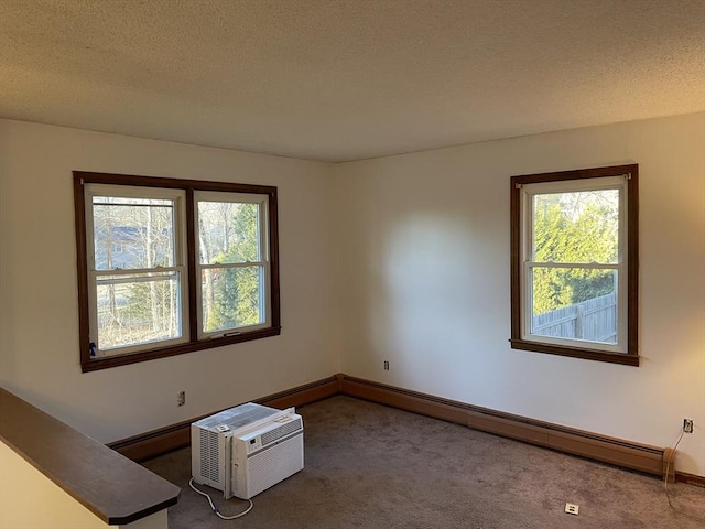 carpeted empty room featuring an AC wall unit, a textured ceiling, and baseboard heating