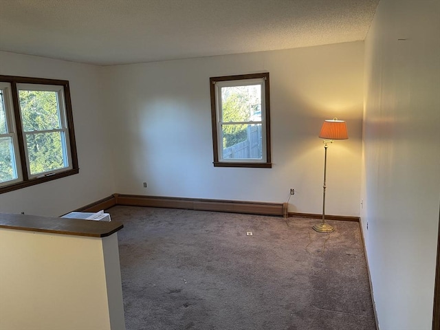 unfurnished room with carpet flooring, a textured ceiling, and a baseboard heating unit