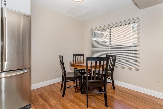 dining area featuring baseboards and light wood-type flooring