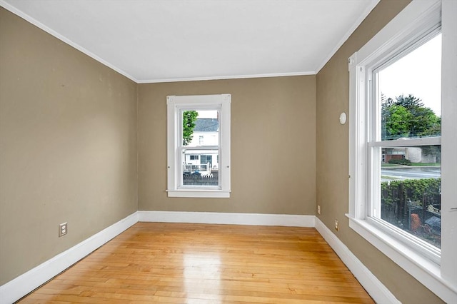 empty room with ornamental molding, light wood-style floors, and baseboards