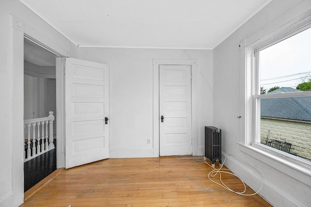 unfurnished bedroom featuring light wood-type flooring, crown molding, and radiator heating unit