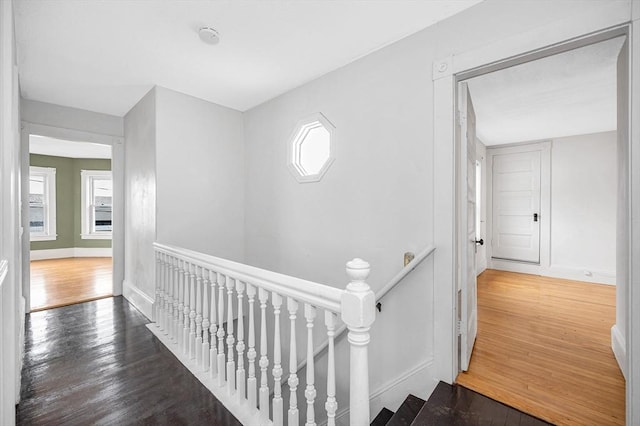 hallway featuring an upstairs landing, wood finished floors, and baseboards