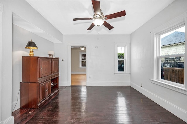 unfurnished room with ceiling fan, dark wood-style flooring, and baseboards