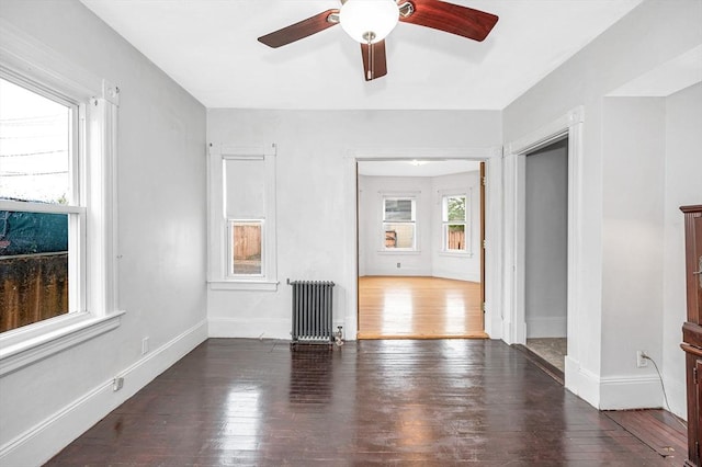 empty room with radiator, hardwood / wood-style floors, a ceiling fan, and baseboards