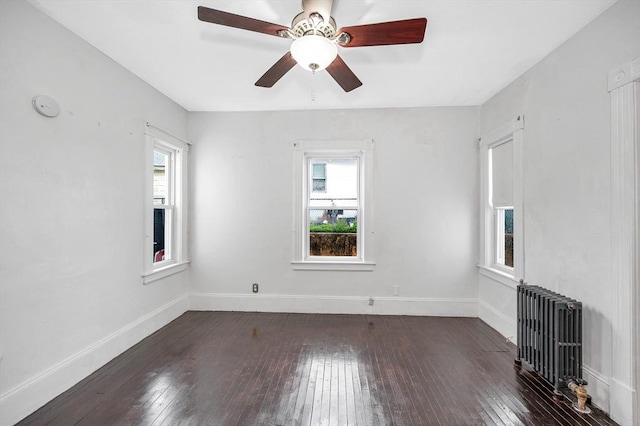 unfurnished room featuring radiator heating unit, hardwood / wood-style floors, and baseboards