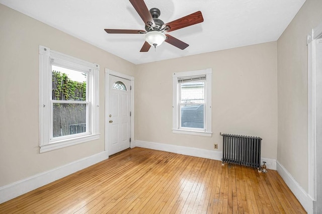 entryway featuring radiator heating unit, light wood finished floors, a ceiling fan, and baseboards