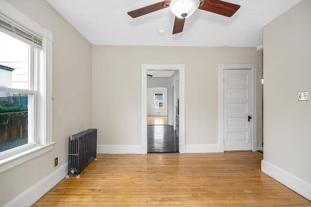 unfurnished room featuring radiator, plenty of natural light, and a ceiling fan