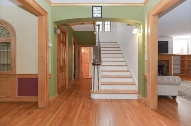 75 William St, Worcester, MA 01609 - staircase featuring arched walkways, wood finished floors, ornamental molding, and a brick fireplace
