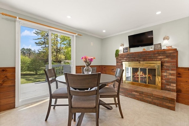 dining space with recessed lighting, ornamental molding, a wainscoted wall, and a fireplace