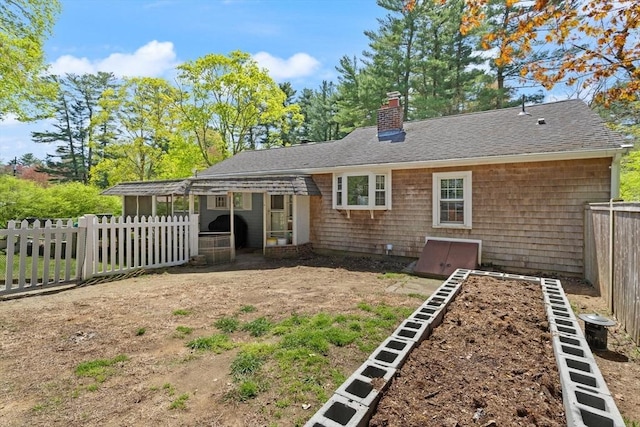 rear view of property with fence, a chimney, and roof with shingles