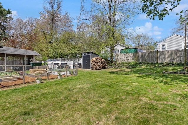 view of yard with a storage shed, fence, an outbuilding, and a vegetable garden