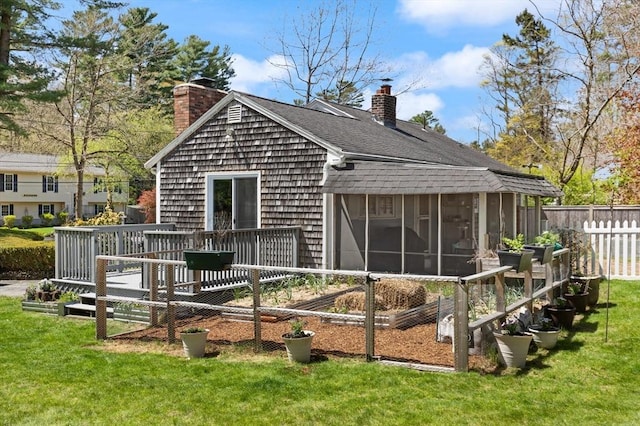 rear view of house with a sunroom, fence, a yard, and a chimney