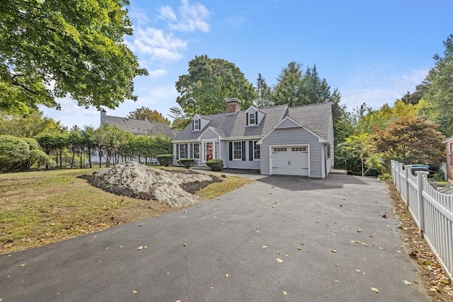 view of front of house featuring an attached garage, fence, and aphalt driveway