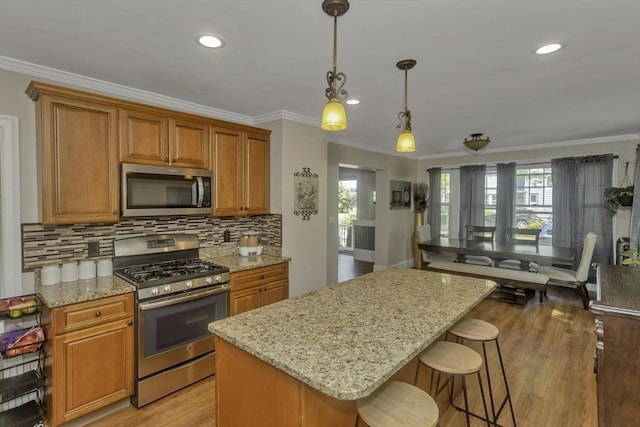 51 Stratford Ter, Springfield, MA 01108 - kitchen with stainless steel appliances, ornamental molding, light wood-style flooring, a breakfast bar, and light stone counters