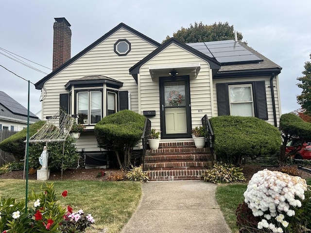 bungalow-style house with solar panels and a chimney