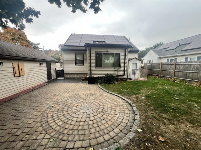 back of house featuring a patio area, fence, solar panels, and a yard