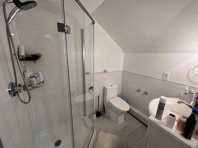 bathroom featuring lofted ceiling, tile walls, a shower stall, and toilet