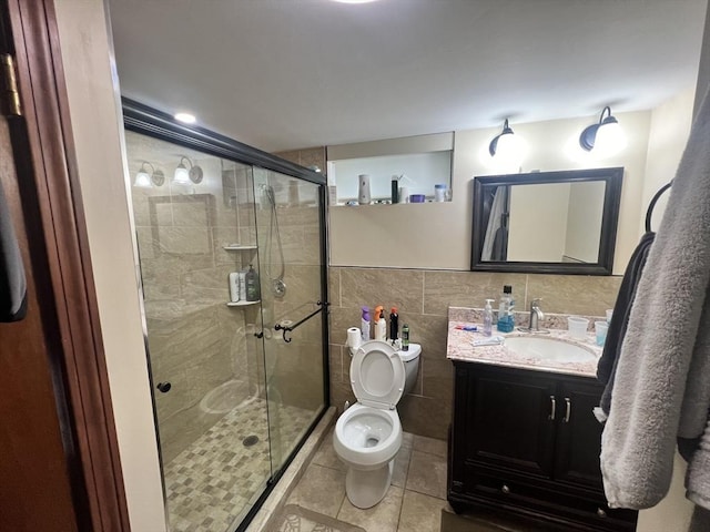 full bath with toilet, vanity, tile walls, a shower stall, and tile patterned floors