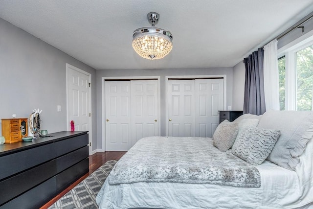 1102 Foxwood Cir Unit 1102, Peabody, MA 01960 - bedroom featuring multiple closets, a chandelier, dark wood finished floors, and baseboards