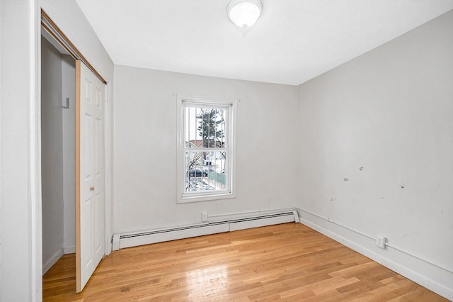 unfurnished bedroom featuring light wood-type flooring and baseboard heating