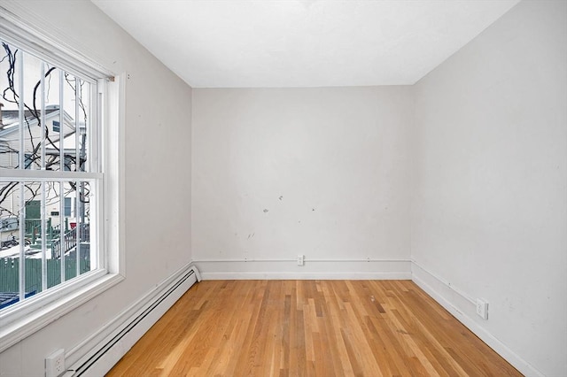 spare room with baseboard heating and light hardwood / wood-style flooring