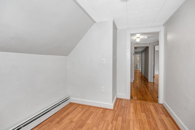 additional living space featuring vaulted ceiling, light hardwood / wood-style flooring, and a baseboard radiator