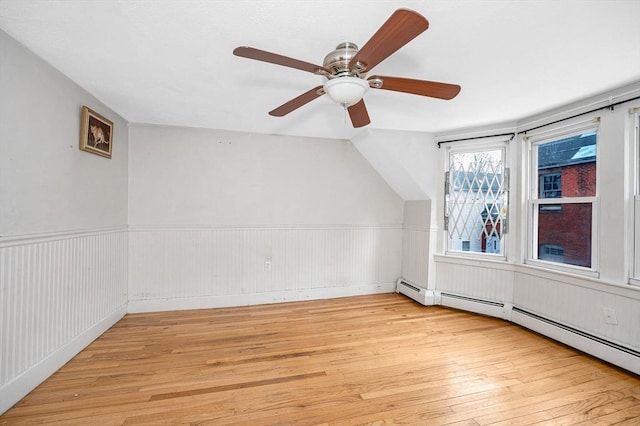 additional living space featuring light hardwood / wood-style floors, baseboard heating, ceiling fan, and vaulted ceiling