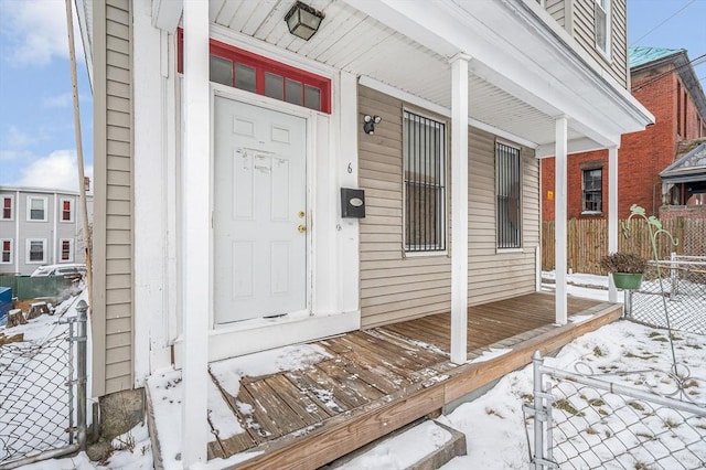 snow covered property entrance with covered porch