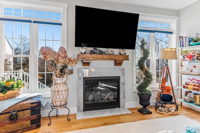 living room with a fireplace, baseboards, and wood finished floors