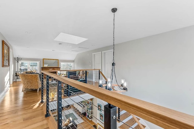 hallway with a skylight, light wood-style flooring, and an upstairs landing