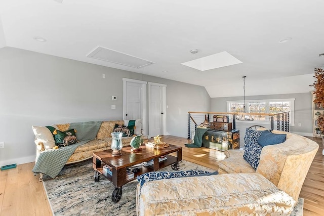 living room featuring lofted ceiling, wood finished floors, and attic access