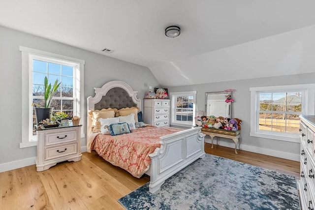 bedroom with light wood finished floors, visible vents, baseboards, and vaulted ceiling