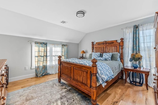 bedroom featuring vaulted ceiling, light wood-type flooring, visible vents, and baseboards
