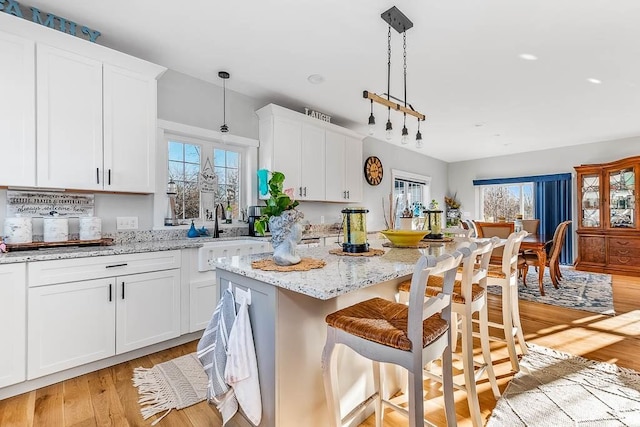 kitchen featuring light wood-style floors, a center island, white cabinetry, and a kitchen bar