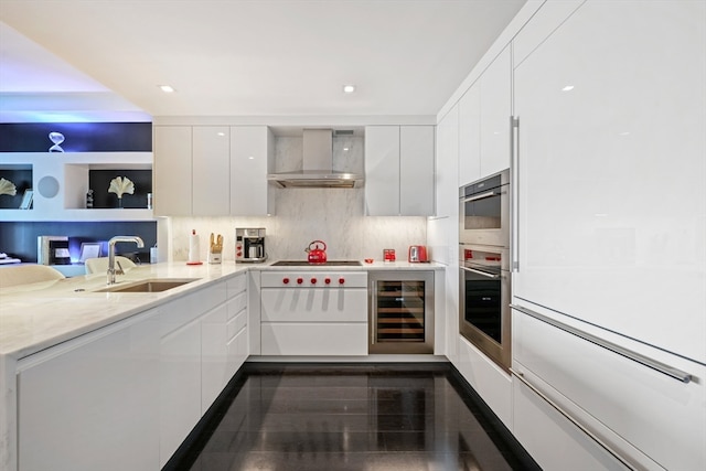 kitchen featuring wine cooler, stainless steel oven, sink, wall chimney range hood, and white cabinetry