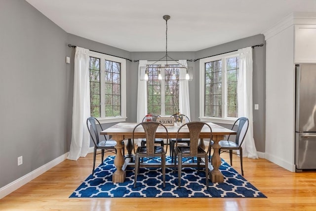 dining room featuring baseboards, a chandelier, and light wood-style floors