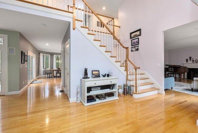 stairway with a towering ceiling, baseboards, and wood finished floors