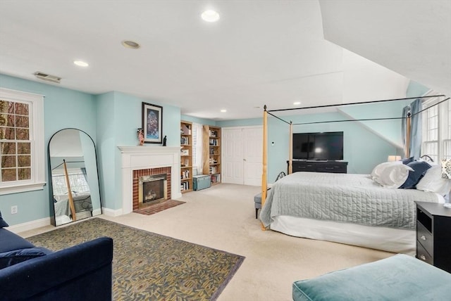 carpeted bedroom with a brick fireplace, baseboards, visible vents, and recessed lighting