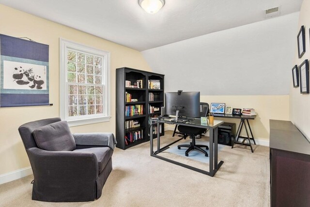 office area with baseboards, visible vents, light colored carpet, and vaulted ceiling